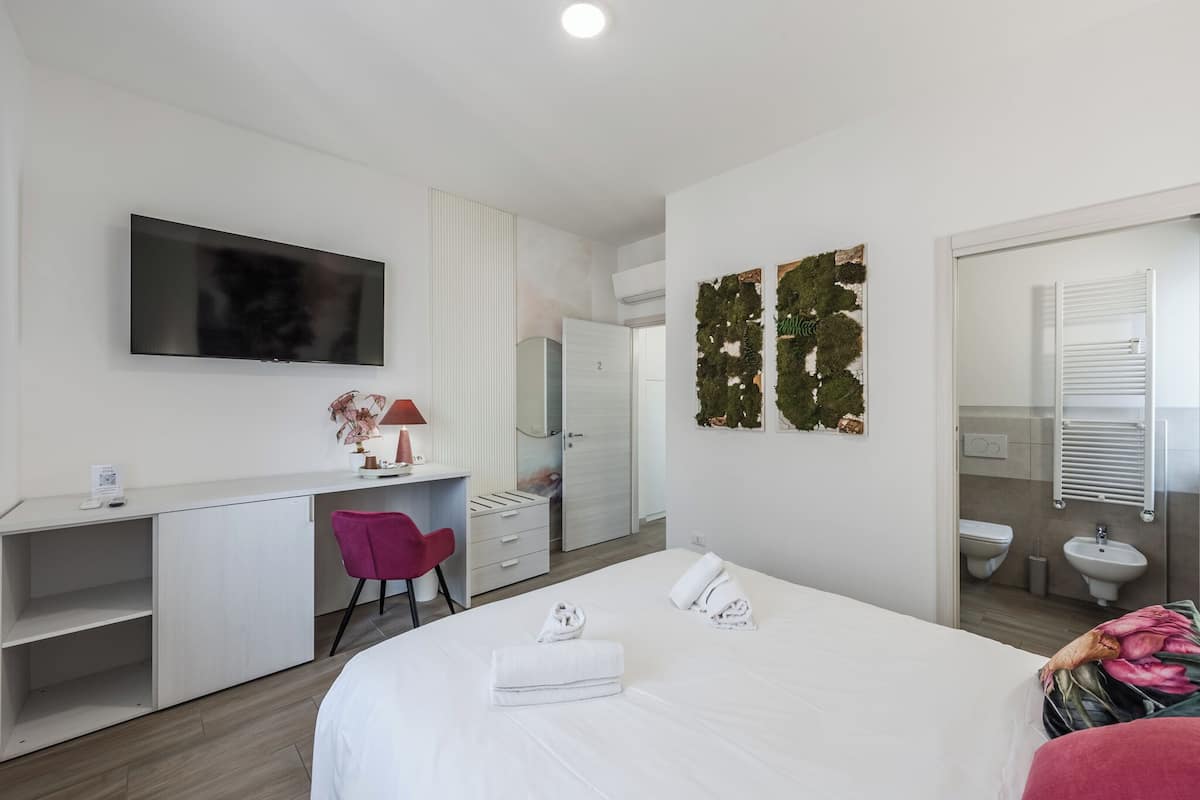 Een hotelkamer met een bed, een bureau, een stoel, een televisie, een kledingkast en een badkamer.