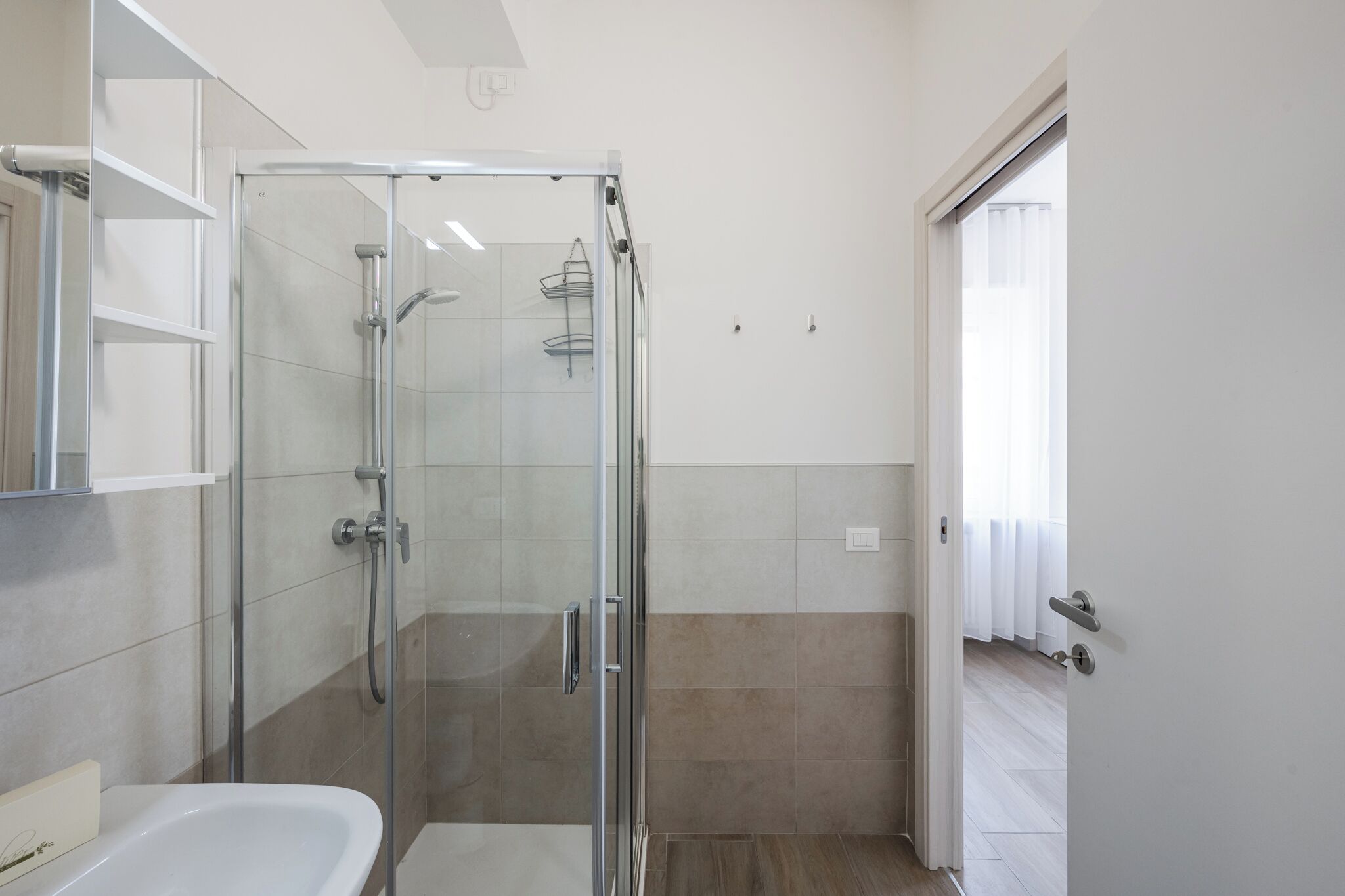 Ein modernes Badezimmer mit einer gläsernen Duschkabine, einer weißen Badewanne und einem weißen Waschtisch.