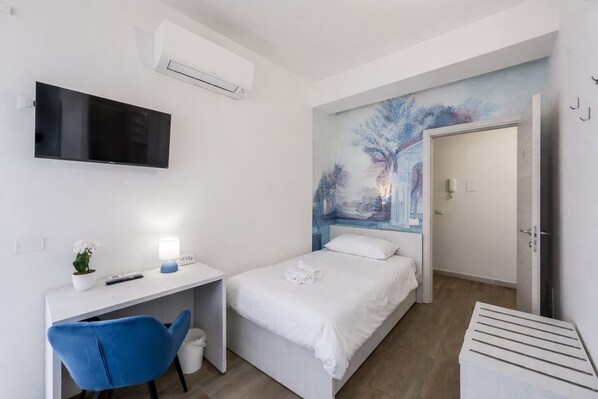 A bedroom with a bed, a desk, a chair, a TV, and a painting on the wall. - VivimiHome-Verona Expo Suites (Verona)