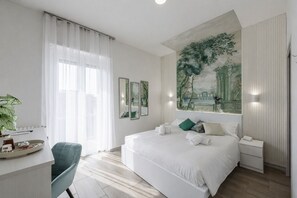 A modern hotel room with a large bed, a desk with a chair, a large window with sheer curtains, and a mural on the wall. - VivimiHome-Verona Expo Suites (Verona)