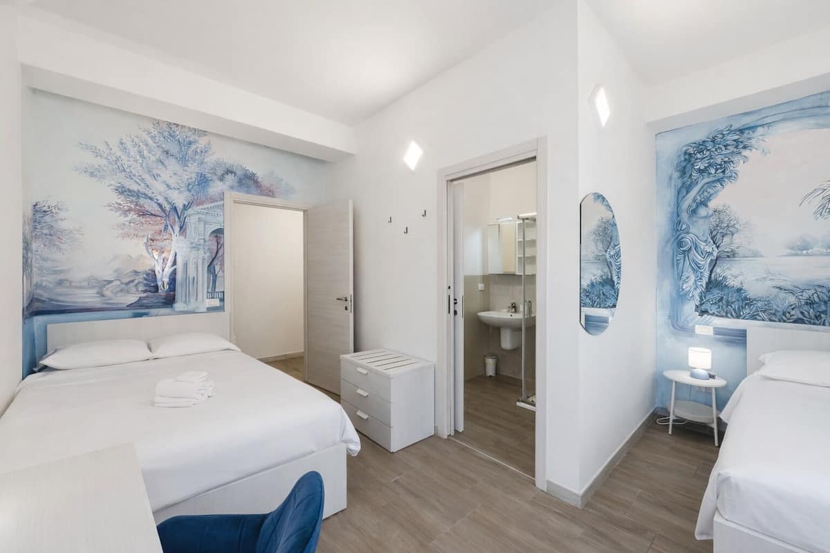 Een hotelkamer met twee bedden, een badkamer en een grote muurschildering.