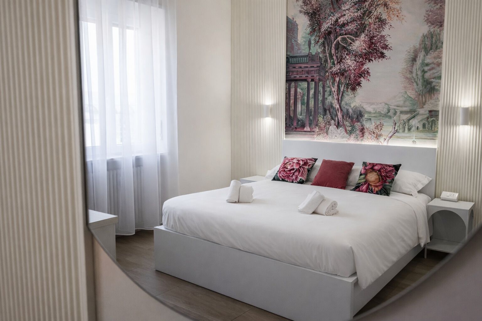 A modern bedroom with a large bed, white bedding, and a decorative wall painting.