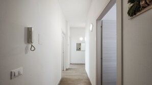 En smal hall med en telefon, en ljusströmbrytare och ett litet fönster längst in.