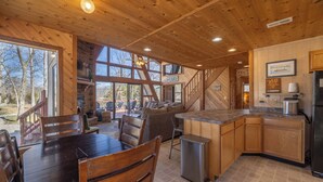 A wooden interior with a dining area, kitchen, and large windows. - Grendel Getaway by Innsbrook Vacations! (Innsbrook)