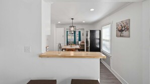 A modern kitchen with a wooden countertop, a black refrigerator, and a dining area with a table and chairs. - Peaceful Stay Near Wake Forest 2 Bedroom Home (Franklinton)