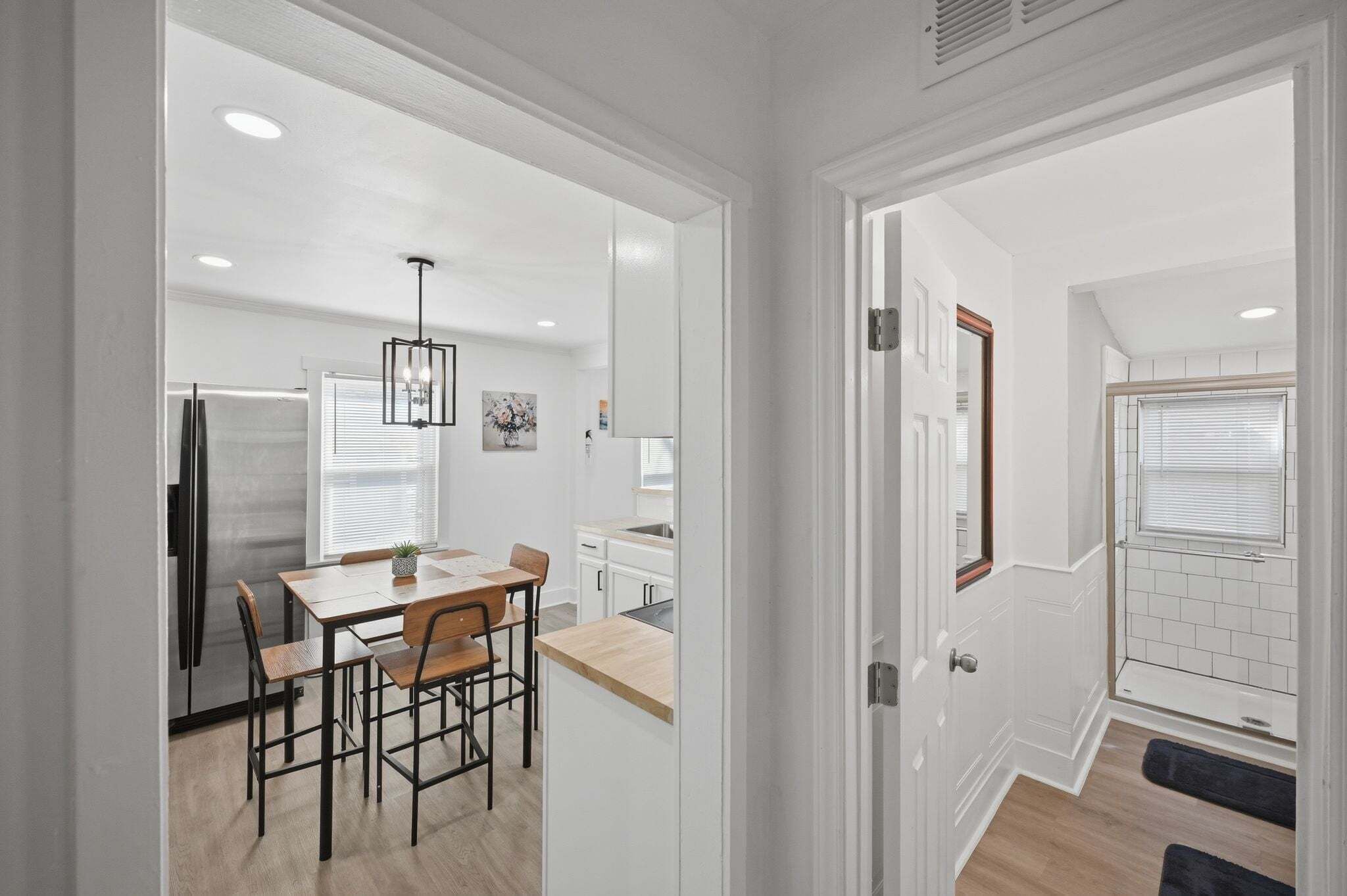 Una cocina moderna con una mesa de comedor, sillas, un refrigerador y una lámpara colgante.