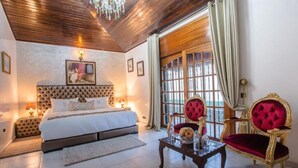 Un dormitorio con cama, mesita de noche, una mesa con silla y ventana con cortinas.