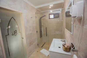 A modern bathroom with a glass shower enclosure, a white sink, and a towel rack. - RIAD SEBTI (Fès)