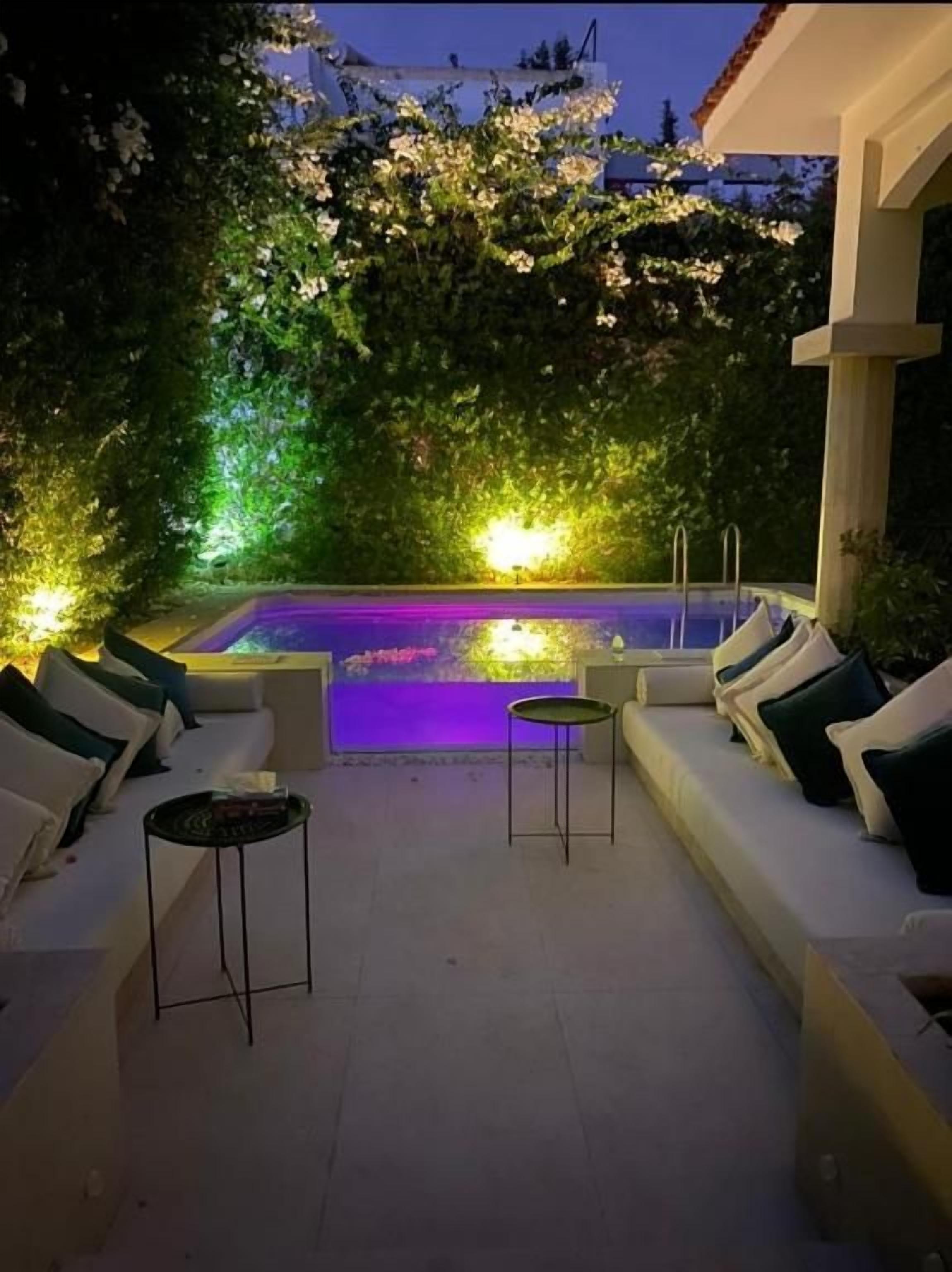 A pool area with a white outdoor seating arrangement and a small table.
