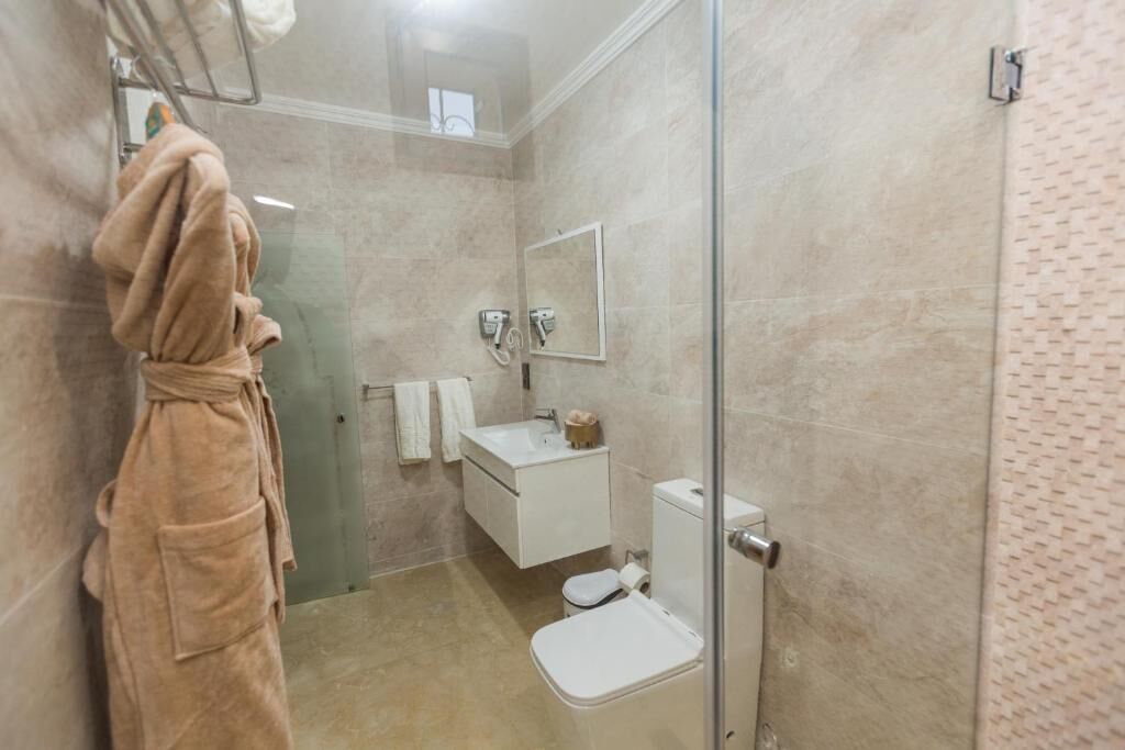 Une salle de bain moderne avec une douche à parois de verre, un lavabo blanc et des toilettes.