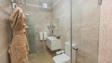 Une salle de bain moderne avec une douche à parois de verre, un lavabo blanc et des toilettes.