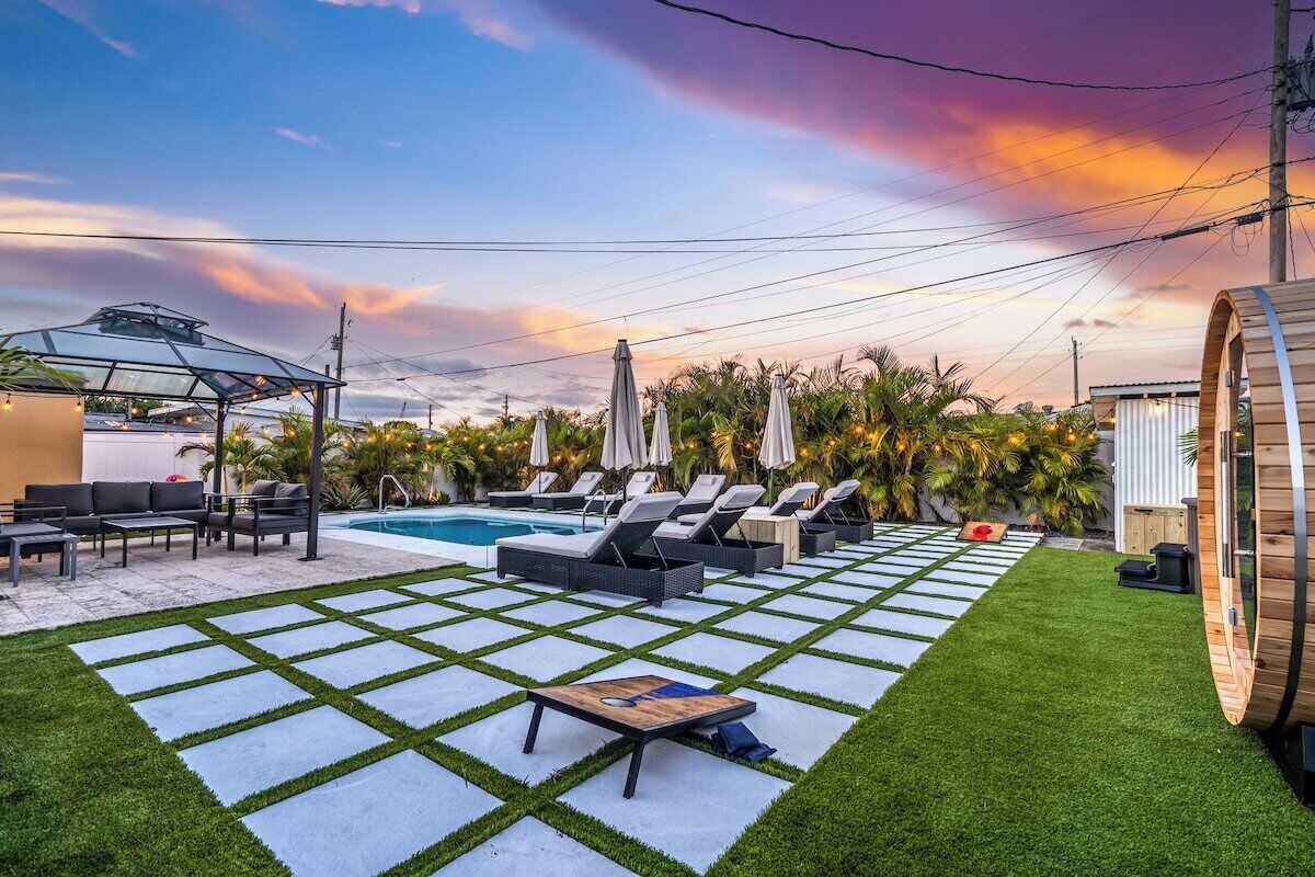 Un área de piscina con sillones de descanso, una mesa y una pérgola.