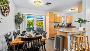 Una cocina moderna con armarios de madera, encimera de granito y un comedor con mesa y sillas de madera.