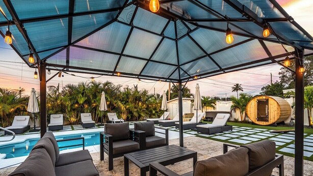 Un espacio de estar al aire libre cubierto con sillones reclinables y una piscina.