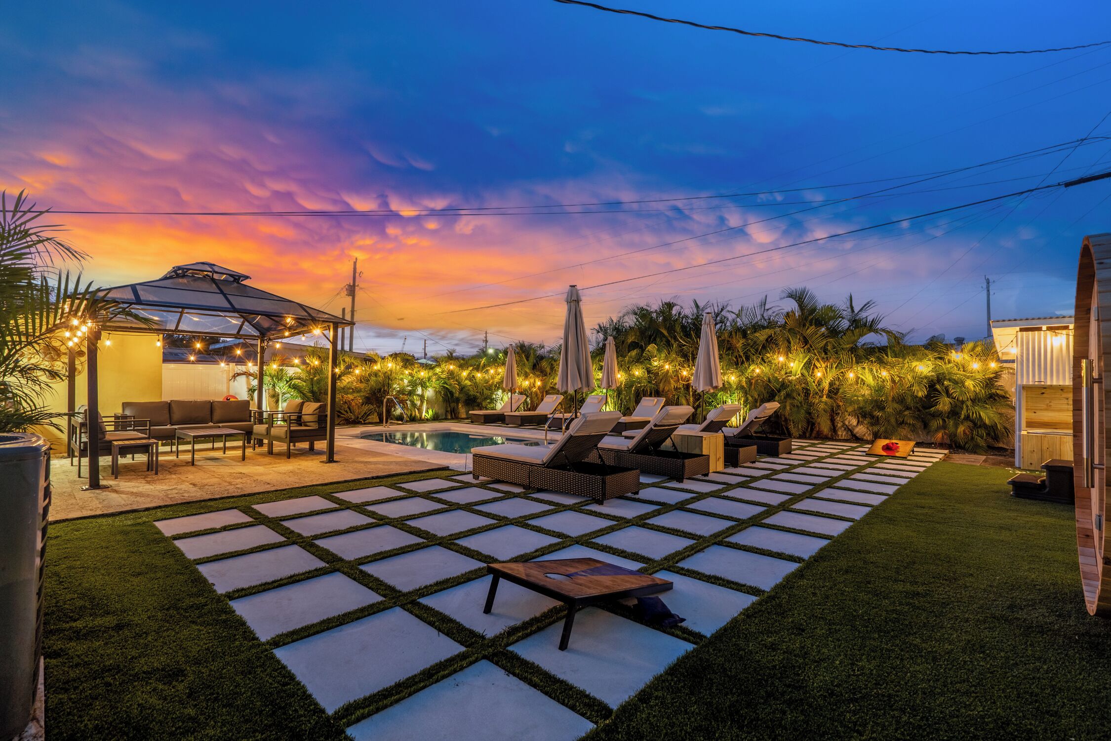 Ein Poolbereich mit Liegestühlen und einer Pergola mit Lichterketten.