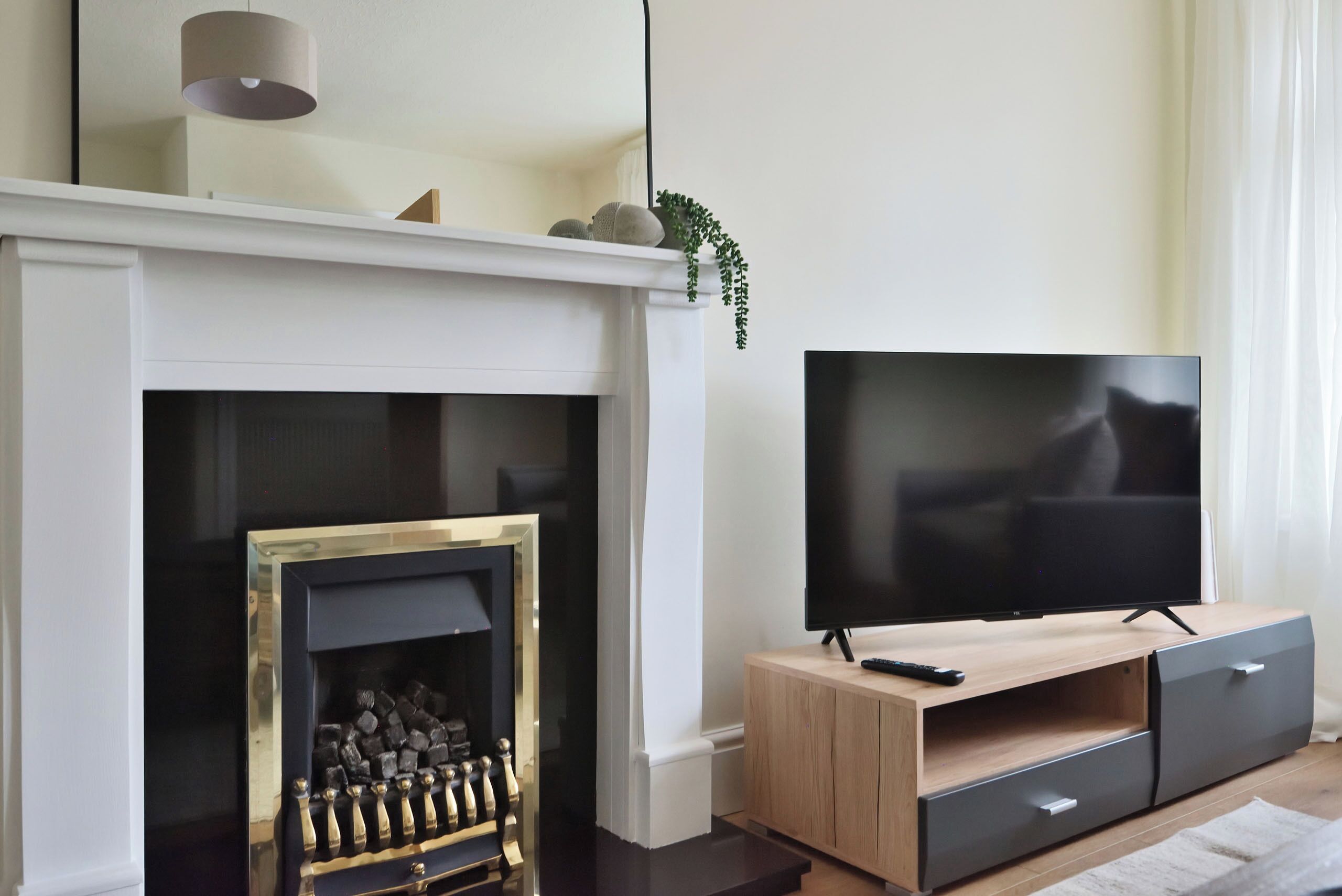 Un salon moderne avec une cheminée, un téléviseur posé sur un meuble en bois et une télécommande.