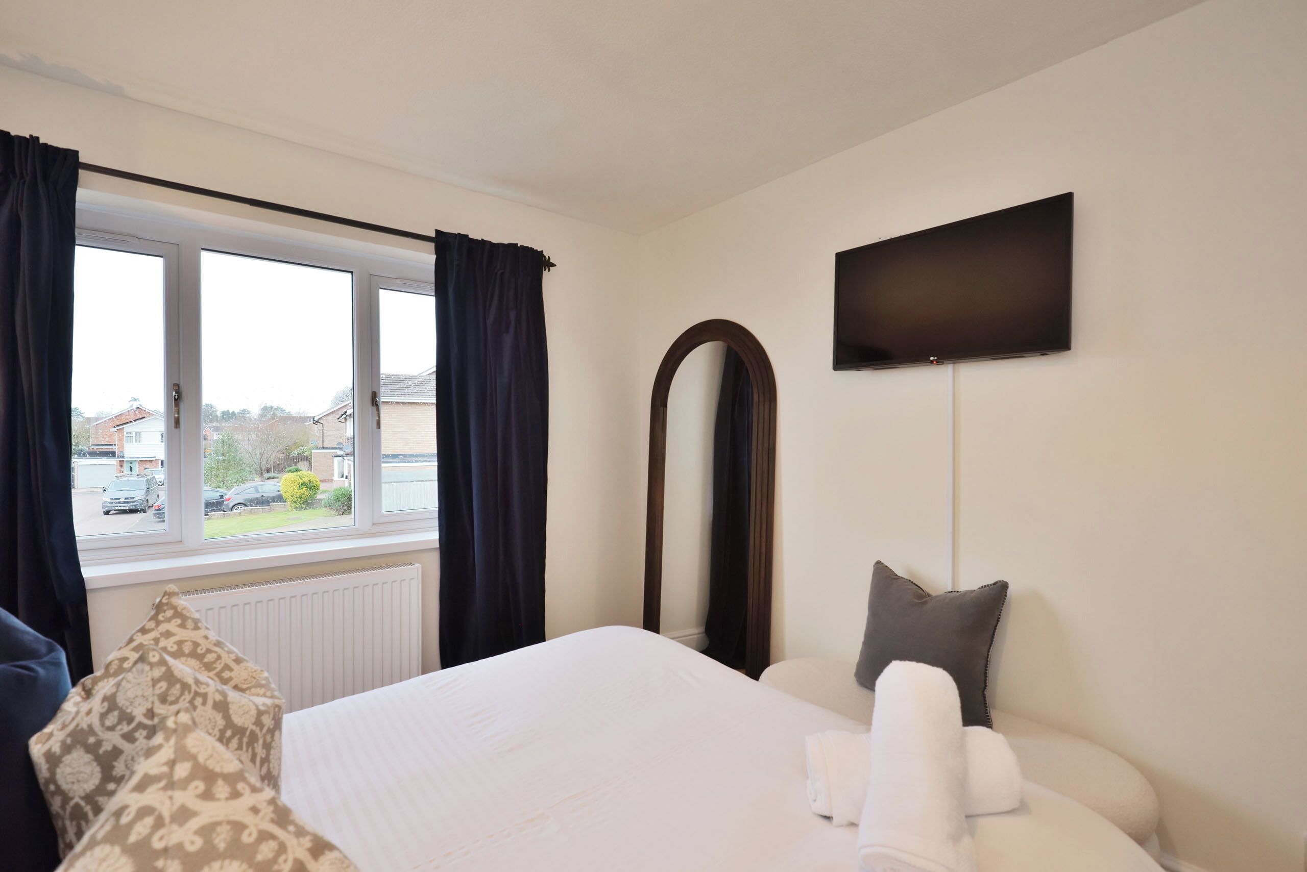 Hotelkamer met een bed, een grote spiegel, een flatscreen televisie en een raam met gordijnen.