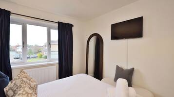 Hotelkamer met een bed, een grote spiegel, een flatscreen televisie en een raam met gordijnen.