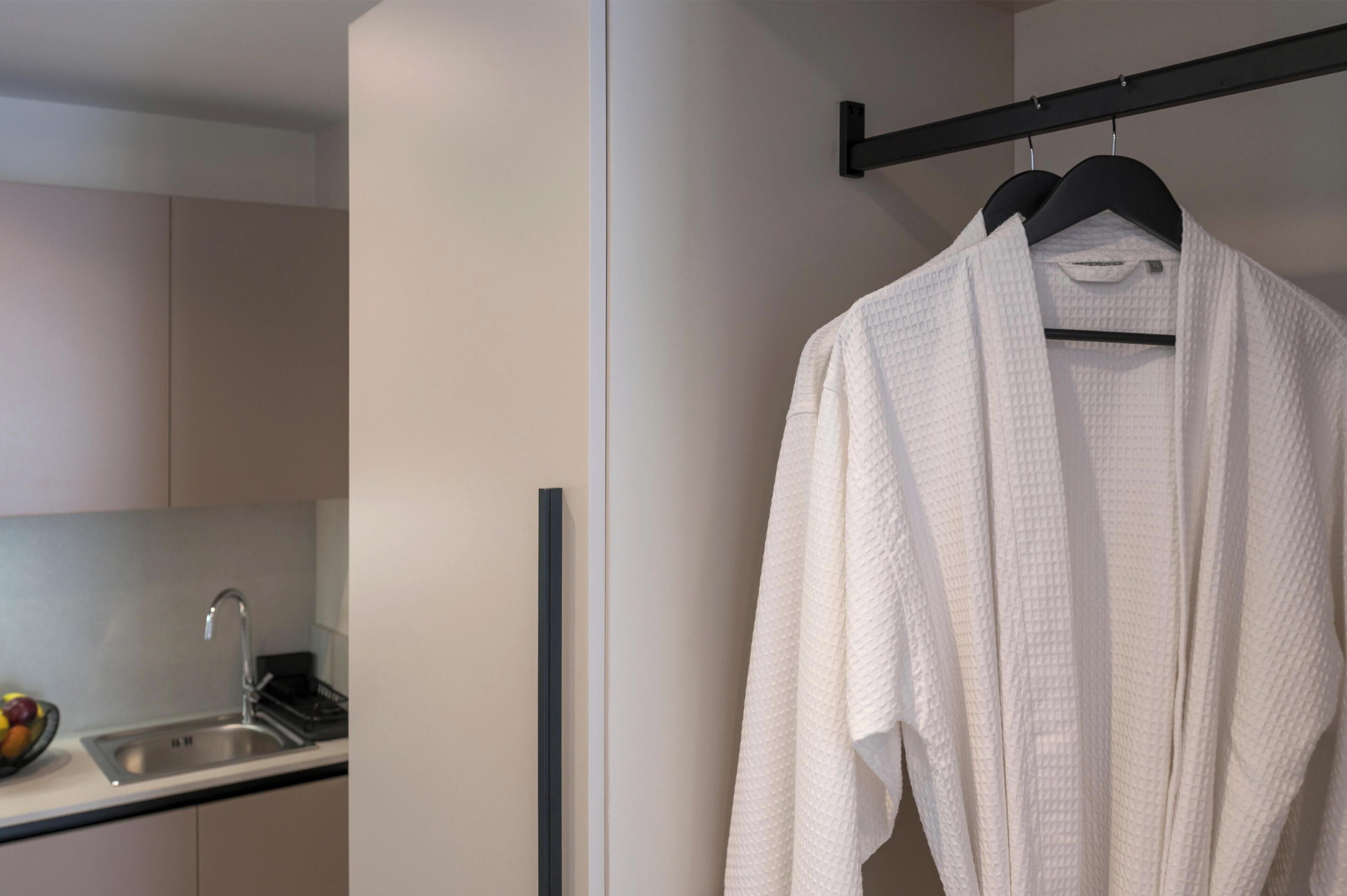 A modern bathroom with a white towel hanging on a black towel rack, a sink with a faucet, and a fruit bowl on the counter.