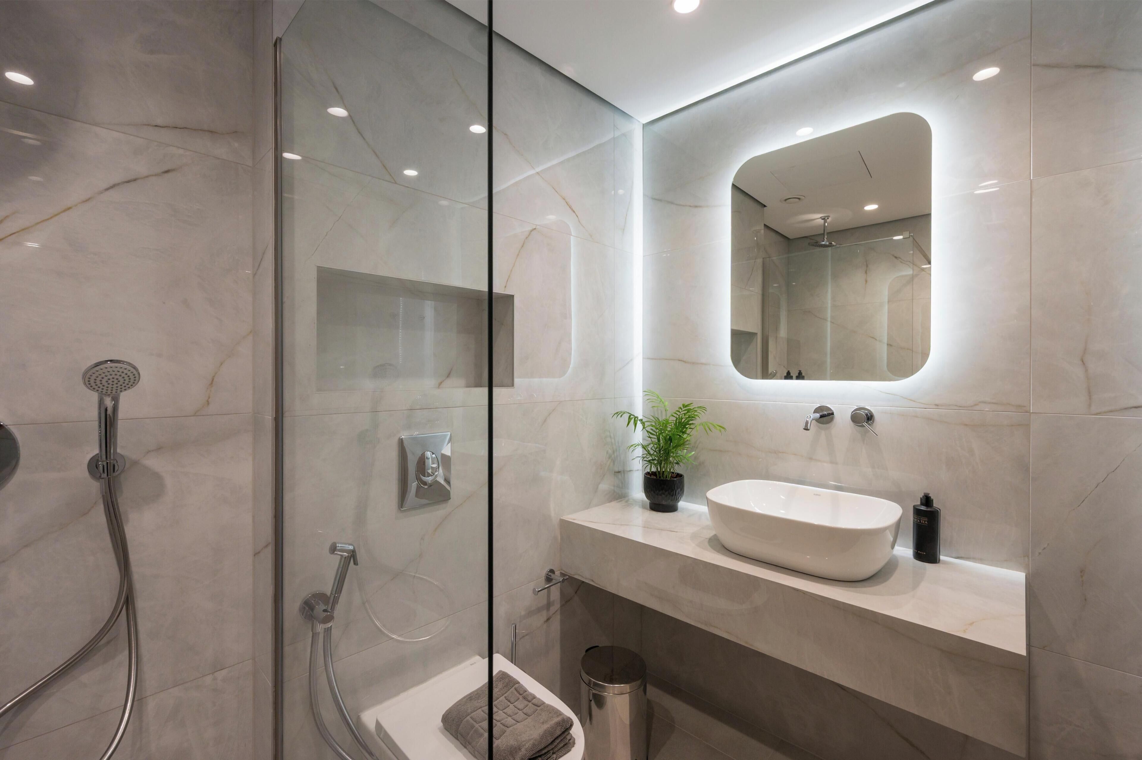 A modern bathroom with a glass-enclosed shower, a white sink, and a mirror above the vanity.