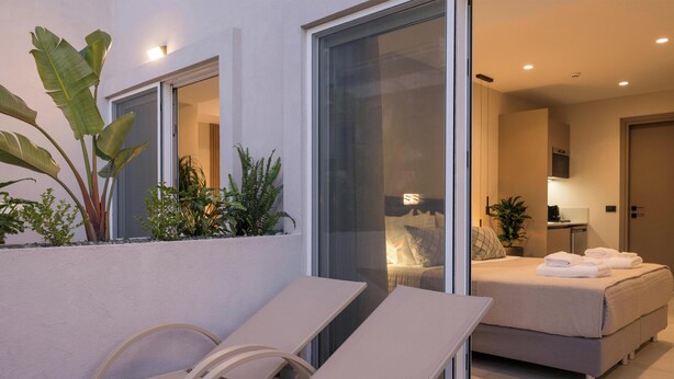 Ein modernes Hotelzimmer mit Balkon, einem Bett und einer Sitzecke mit Stühlen.