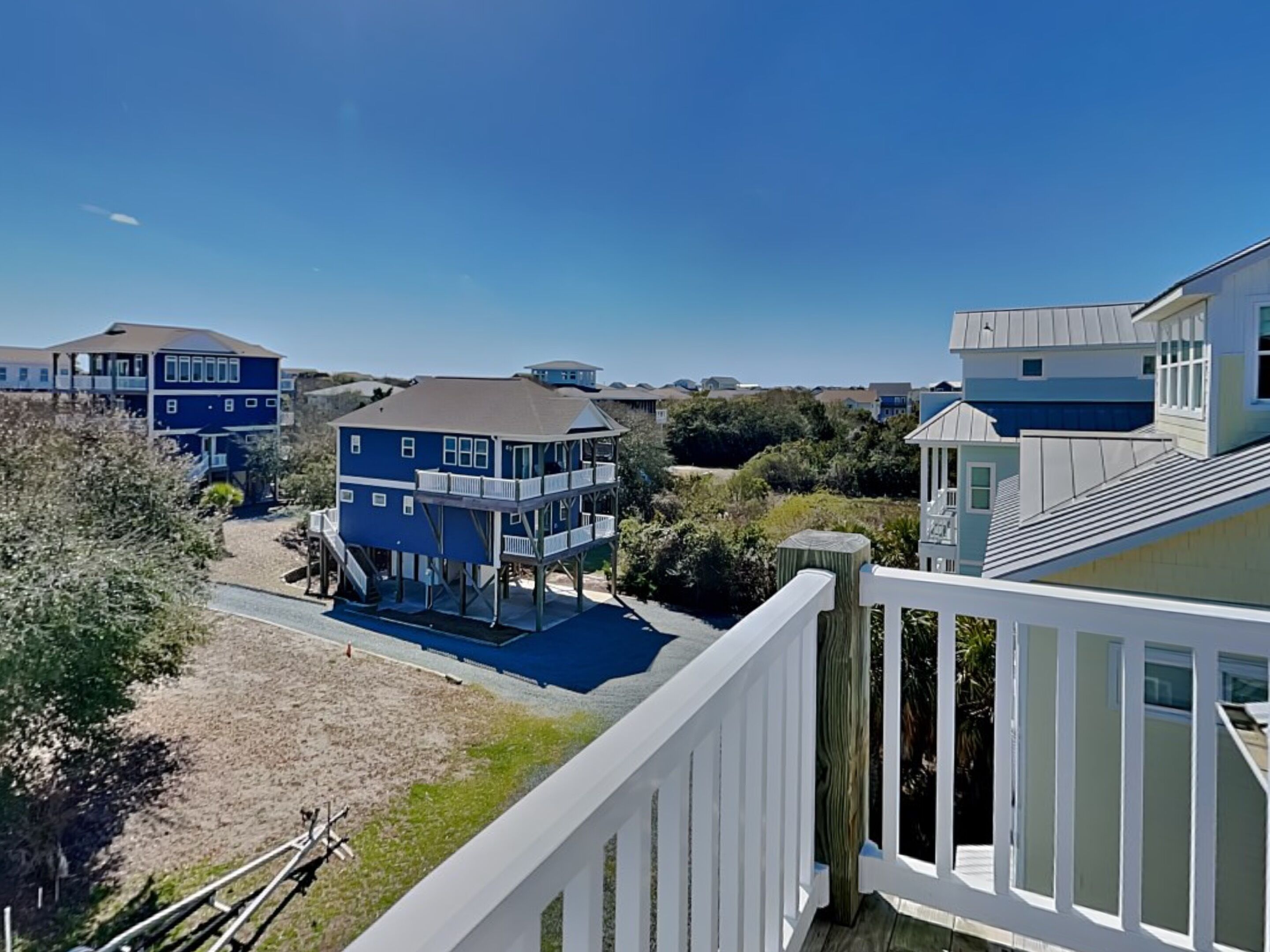 Un quartier résidentiel situé sur la côte, composé de nombreuses maisons à deux étages, dont certaines sont dotées de terrasses surélevées, et où le ciel est dégagé.
