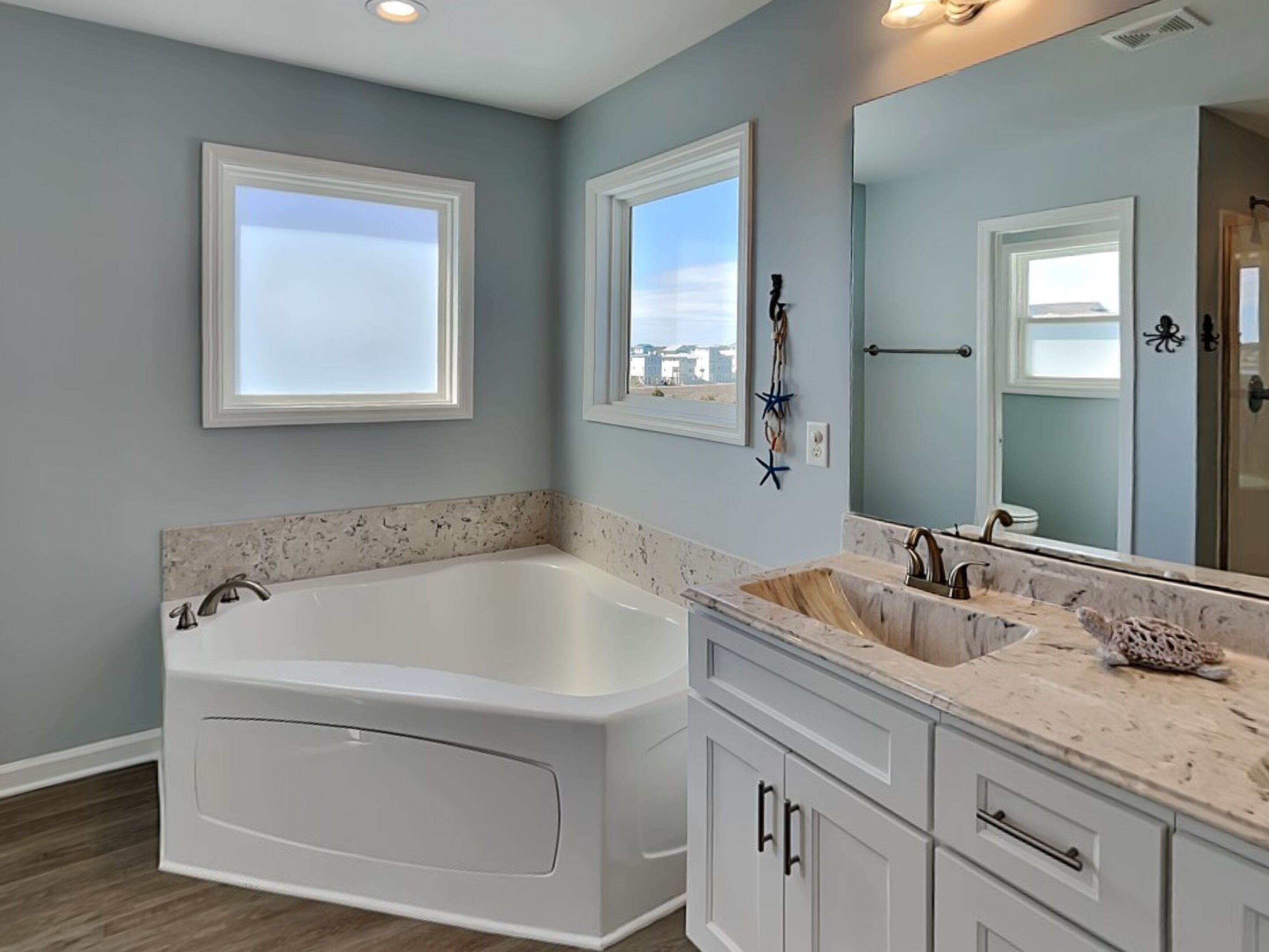 A bathroom with a large bathtub, a vanity with a sink, and a mirror.
