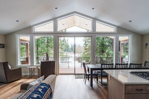 A modern kitchen with a large island, a dining area, and a cozy seating space with a view of trees.