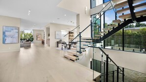 Un interior moderno con una escalera, un comedor y obras de arte en las paredes.