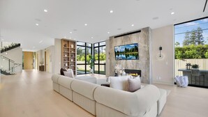 Un salón amplio con un sofá seccional grande, una chimenea y un televisor montado en la pared.