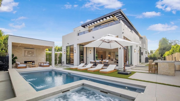Una casa moderna con piscina, zona de estar exterior y bañera de hidromasaje.