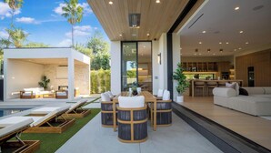 Un espacio exterior moderno con piscina, sillones de descanso y un comedor.