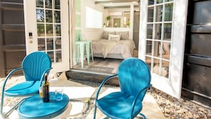 An open door leading to a bedroom with a bed, a bedside table, and a chair. - Scenic Canyon Lake Container Retreat (Canyon Lake)