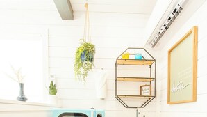 A compact kitchen with a microwave, a small refrigerator, a wooden countertop, a hanging plant, and a shelf with toiletries. - Scenic Canyon Lake Container Retreat (Canyon Lake)