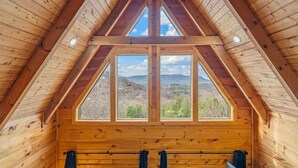Una cabaña de madera con techo triangular y ventanas amplias que ofrecen vistas del paisaje.