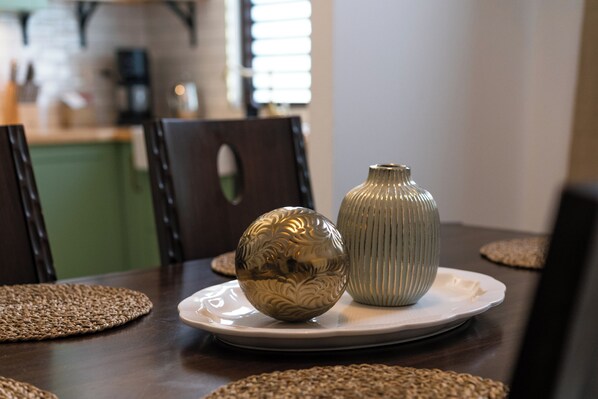 Una mesa de comedor con un plato decorativo, un jarrón y caminos de mesa tejidos.