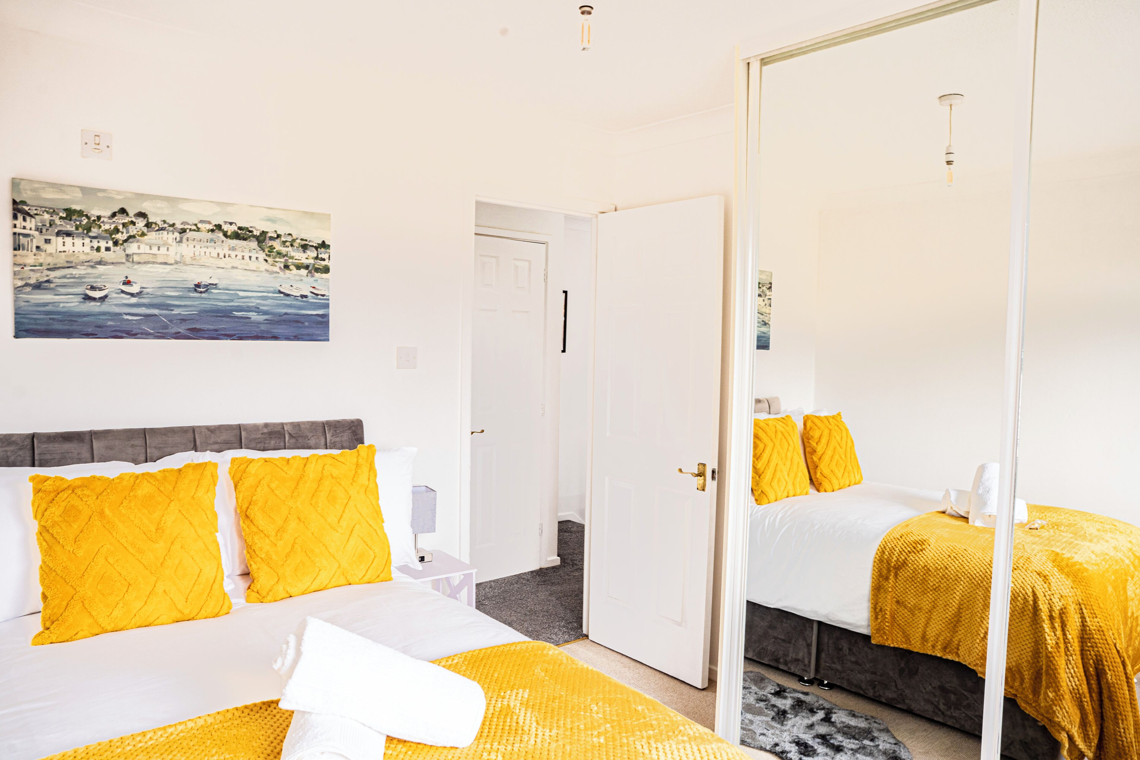 Une chambre d’hôtel avec deux lits, un tableau accroché au mur et un miroir qui reflète la pièce.