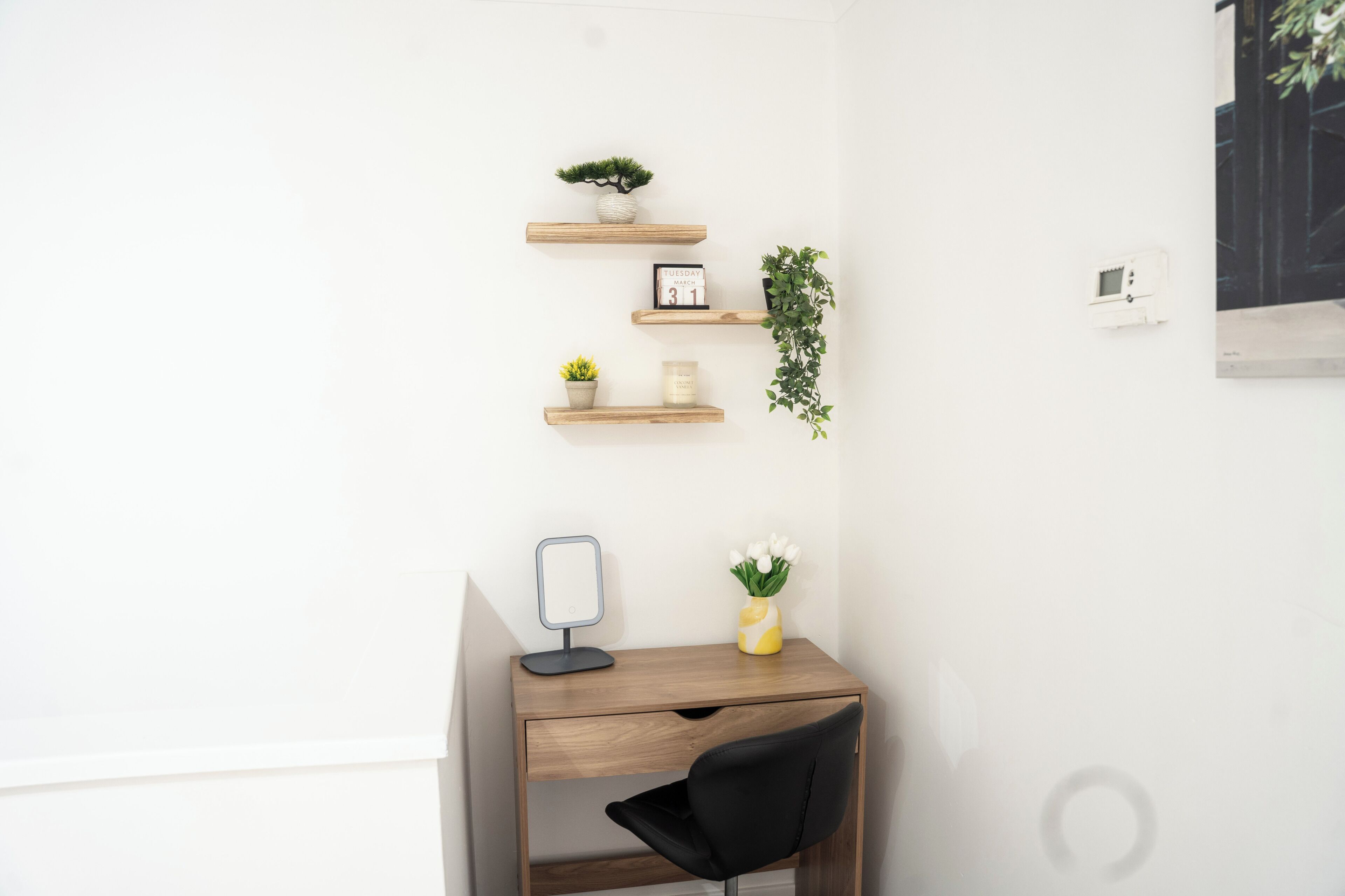 Een hoekbureau met een spiegel, een kleine plant in een pot en een agenda.