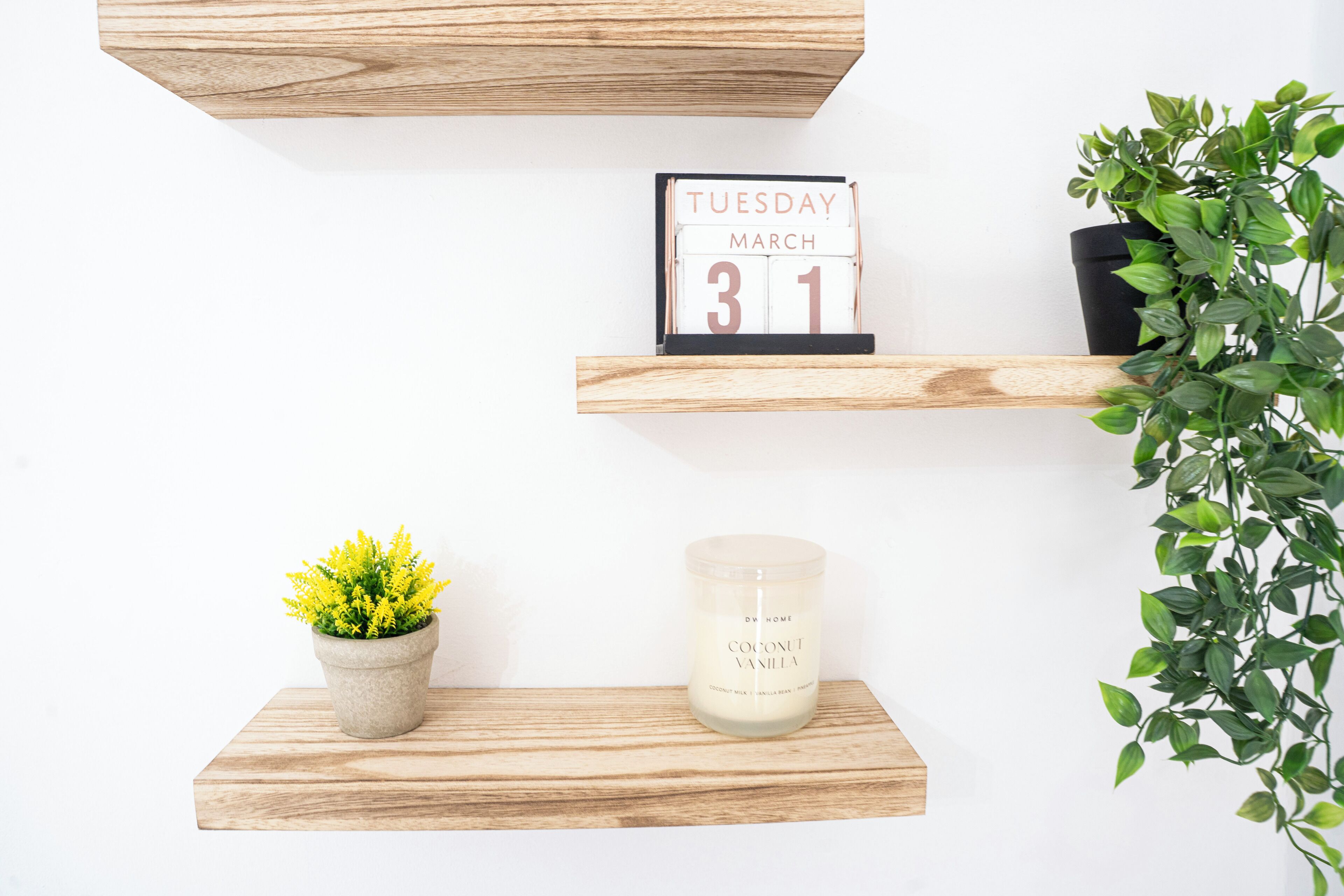 Een houten plank met een agenda, een kaars en een plant in pot.