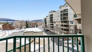 A multi-story building with balconies, a parking area, and a view of snow-capped mountains. - Mountain Escape in Frisco | 2BR w/ Shared Hot Tub (Frisco)