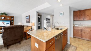 A modern kitchen with a granite countertop, wooden cabinets, and a built-in dishwasher. - Mountain Escape in Frisco | 2BR w/ Shared Hot Tub (Frisco)