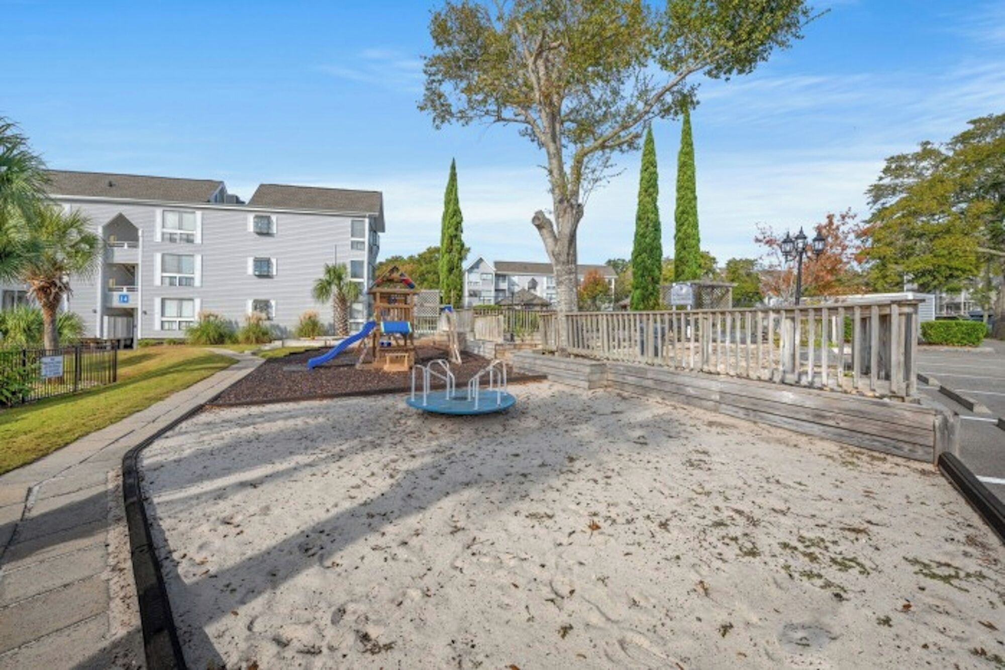 A playground with a slide, a small play structure, and a sandy area.