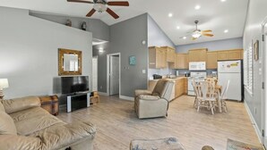A living room with a sofa, a television, a ceiling fan, and a kitchen area with cabinets and appliances. - 3 Bedroom House (7033) in Ocean Lakes Campground (Myrtle Beach)