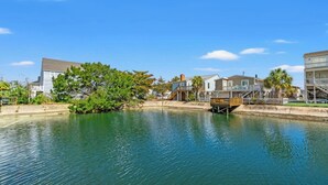 Une propriété située au bord de l’eau, dotée d’un quai, une maison avec un balcon et un bâtiment avec un toit en pente.