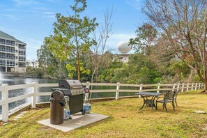 A waterfront patio with a grill, a trash can, and a table with chairs. - Ocean Keyes Seashore 4622 - Walk to Beach (North Myrtle Beach)