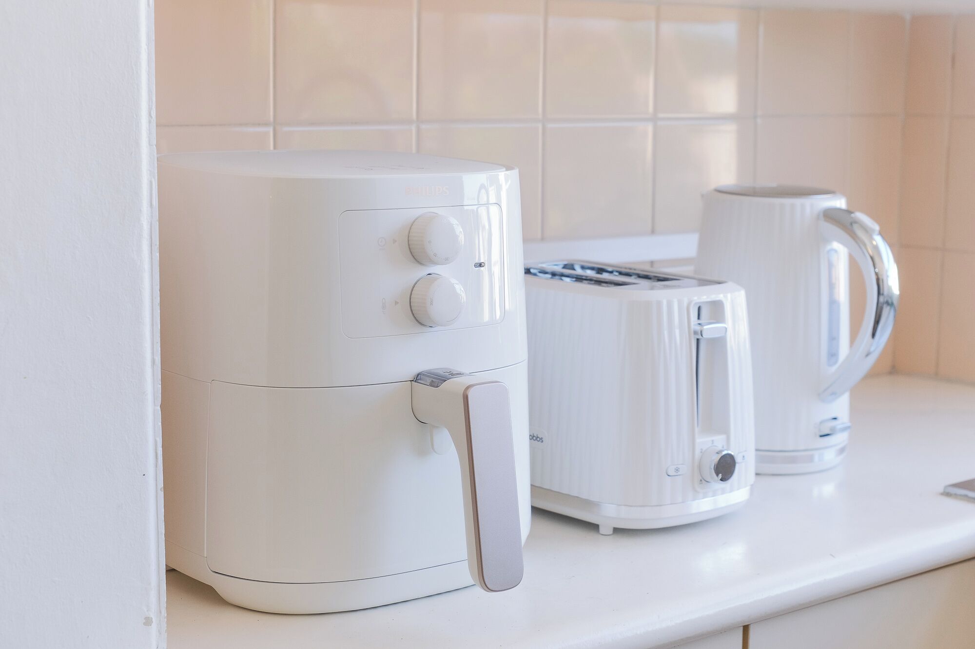 A kitchen with a white air fryer, a toaster, and a kettle on the counter.