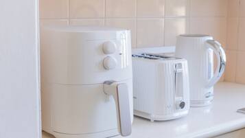 A kitchen with a white air fryer, a toaster, and a kettle on the counter.