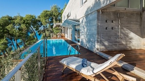 A modern house with a swimming pool, wooden deck, and a view of the sea. - Luxury Villa Azure Bay by the sea with heated pool and BBQ, perfect for families and pets (Bobovišća)