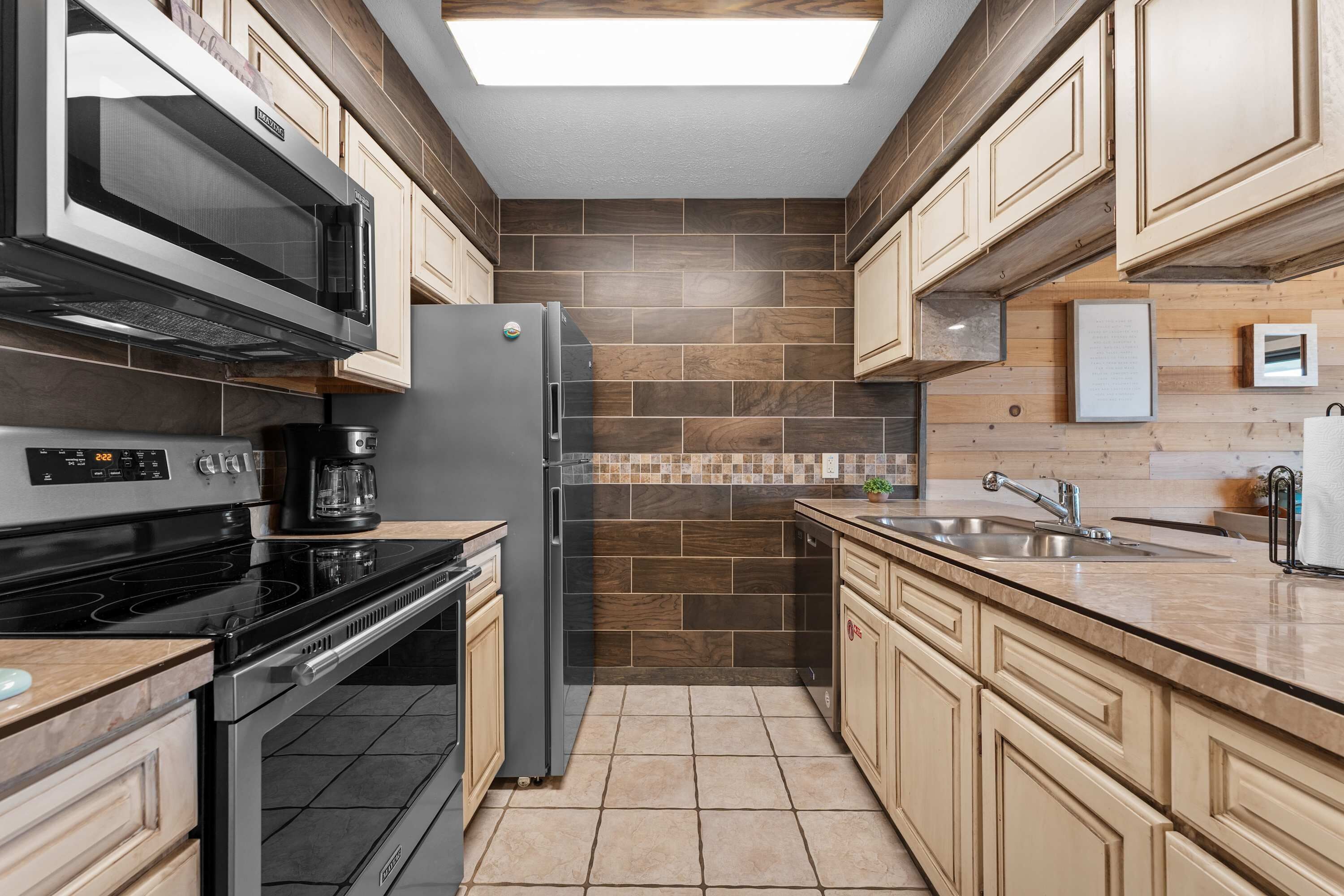 A kitchen with a microwave, stove, refrigerator, and sink.