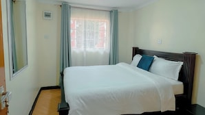 Ein Schlafzimmer mit Bett, einem Fenster mit Vorhängen, einer Deckenleuchte und einer Tür.